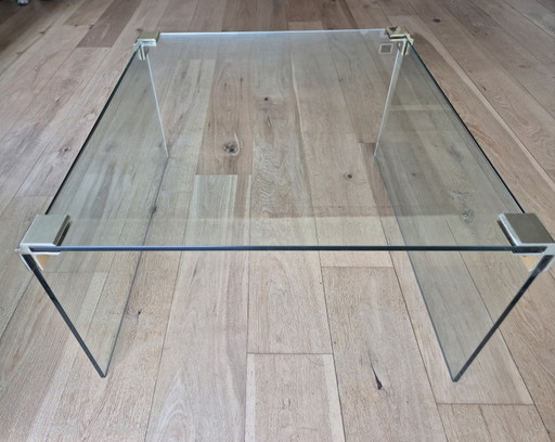 Glass coffee table with brass-colored details.
