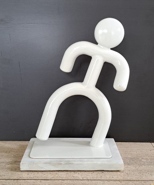 Dancing man made of metal on marble base