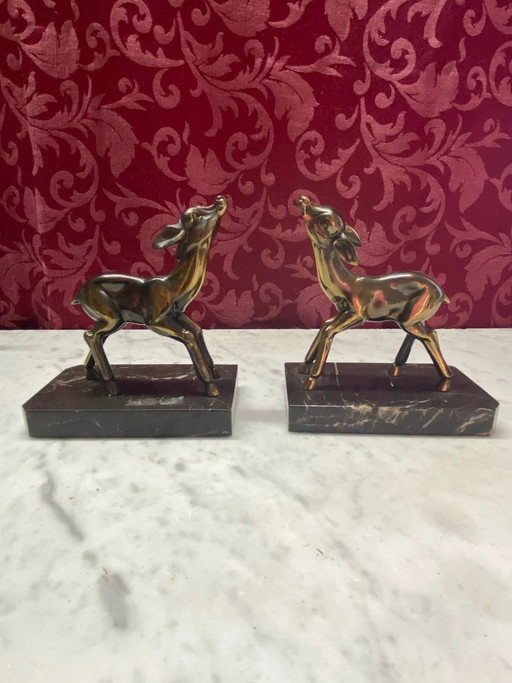 Deux serre-livres en régule à patine bronze représentant des faons, sur un socle en marbre noir, style Art déco.