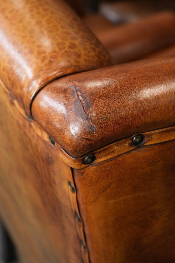 Image 1 of Grote oorfauteuil gemaakt van schapenleer met zwarte biezen en siernagels