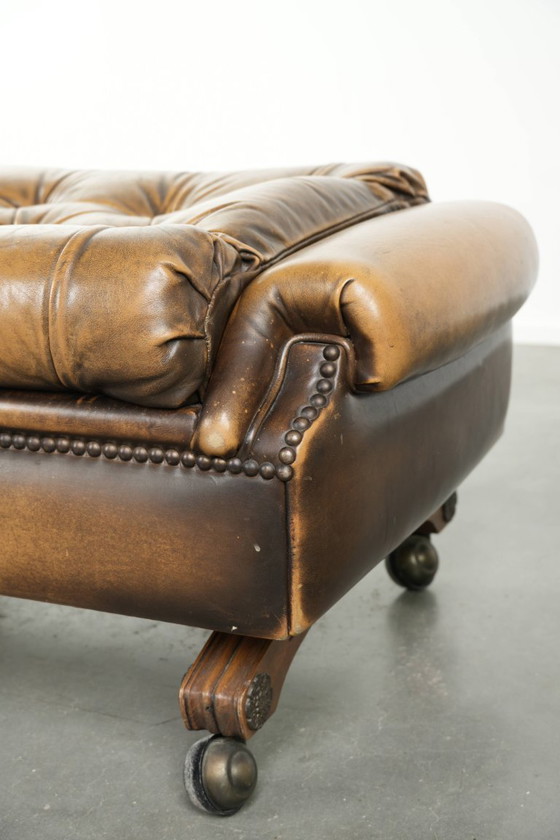Image 1 of Exclusivo y elegante puf inglés Chesterfield de piel de vacuno con ruedas y acabado con clavos decorativos.