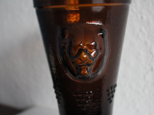Antique wine tankard made of heavy amber glass with lion heads and paws