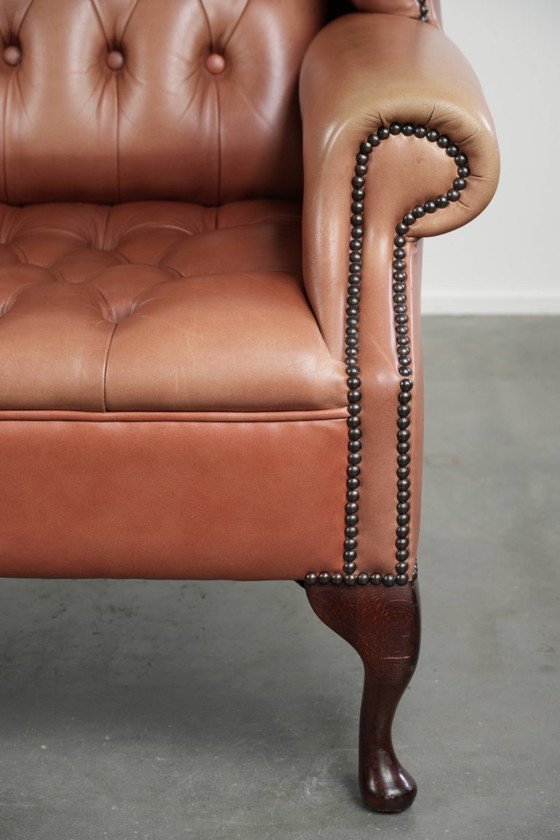 Image 1 of Fauteuil Chesterfield à oreilles en cuir de vachette anglais, assise capitonnée, avec une belle patine et de jolies couleurs.