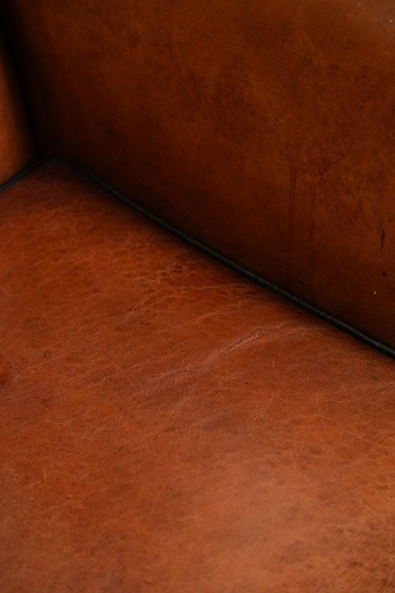 Image 1 of Grote oorfauteuil gemaakt van schapenleer met zwarte biezen en siernagels