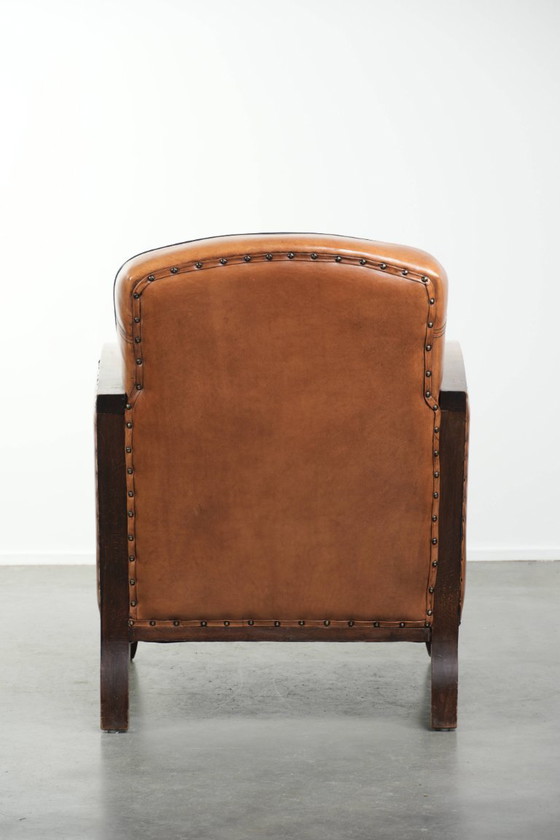 Image 1 of Schapenleren art Deco fauteuil met mooi houtsnijwerk en zwarte biezen