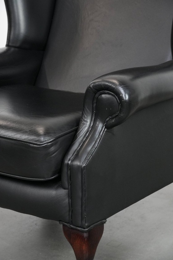 Image 1 of Smooth black cowhide Chesterfield wingback armchair in English style with color-matched piping