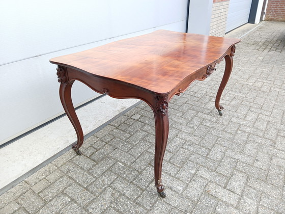 Image 1 of The antique dining table is made of mahogany and has a Louis XV style.
