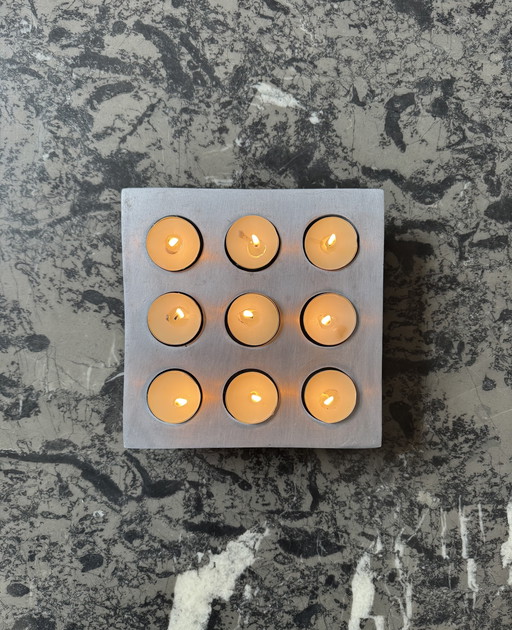 Brushed aluminum candle holder in a 1970s Scandinavian brutalist style