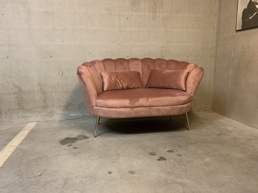 Banc rose à deux places avec des pieds dorés.