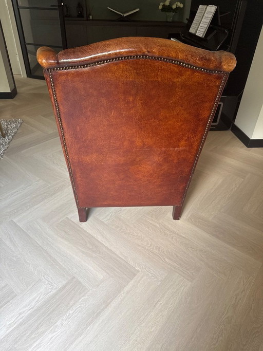 Poltrona antica con alette laterali in pelle di pecora, color cognac