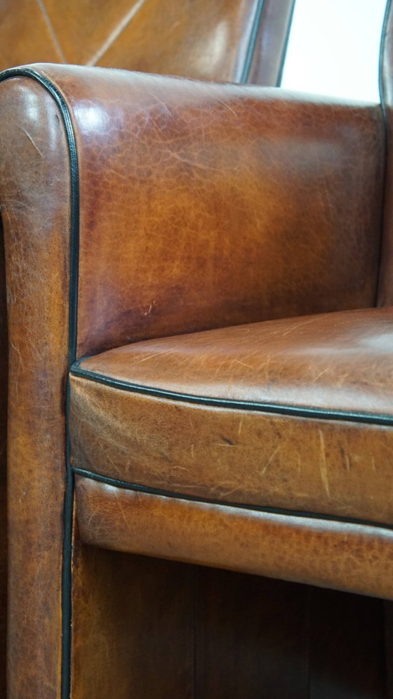 Image 1 of 2 x Vintage schapenleren eetkamerstoel met zwarte biezen op wieltjes