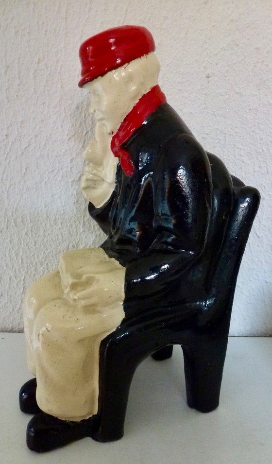 Image 1 of A set of decorative bookends depicting an elderly couple sitting on chairs.