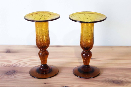 Een paar BIOT kaarsenstandaards van amberkleurig glas.
