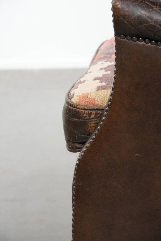 Image 1 of Subtiele donkerbruine fauteuil gemaakt van rundleer met een omkeerbaar Kelim zitkussen