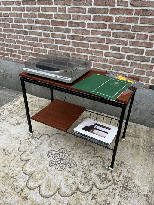 Mueble estéreo antiguo de teca con estructura de metal negro y ruedas giratorias.