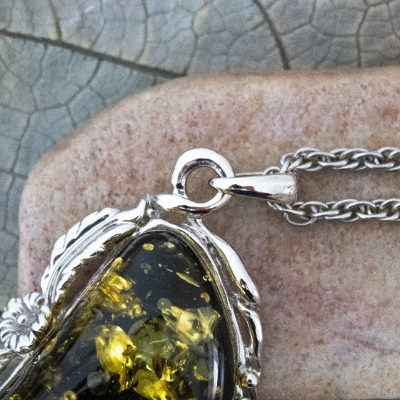 Image 1 of Grande ciondolo in ambra baltica verde: incastonato in metallo color argento con decorazioni floreali.