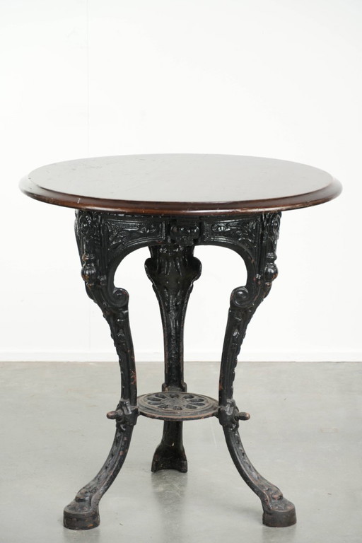 Antique English pub/bistro/side table from the 19th century with a cast iron base and a round wooden tabletop.