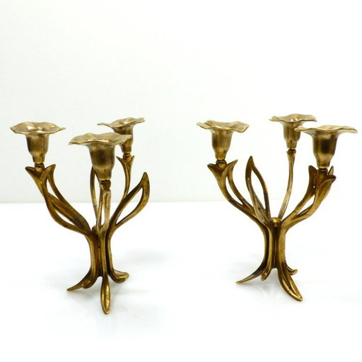 Een paar messing kandelaars met drie lichtpunten op een statief, versierd met organische bloemmotieven, circa 1960-1970.