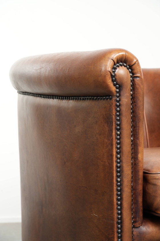 Image 1 of Poltrona club in montone color cognac caldo, rifinita con borchie decorative.