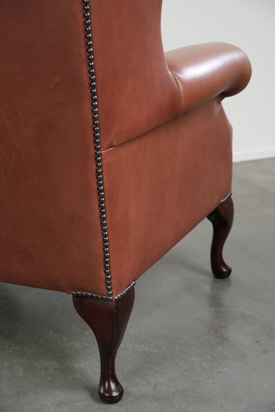 Image 1 of Fauteuil Chesterfield à oreilles en cuir de vachette anglais, assise capitonnée, avec une belle patine et de jolies couleurs.