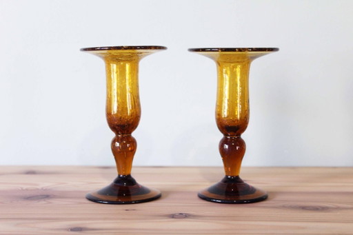 Een paar BIOT kaarsenstandaards van amberkleurig glas.