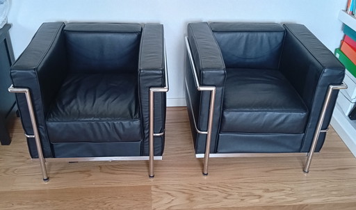 Een set van twee zwarte leren fauteuils en een bank.