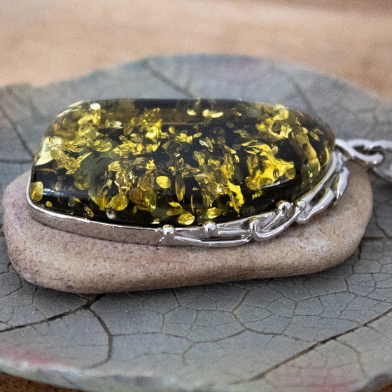 Image 1 of Grande ciondolo in ambra baltica verde: incastonato in metallo color argento con decorazioni floreali.
