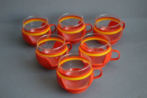 12 vintage glazen theekopjes met geel-oranje strepen en oranje plastic houders.
