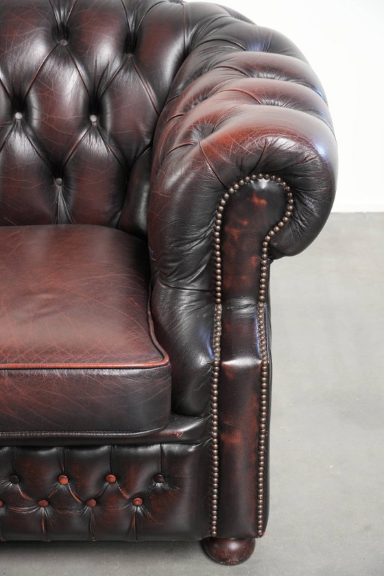 Image 1 of Canapé Chesterfield 2 places en cuir de vachette anglais ancien rouge/marron, au style magnifique et au charme intemporel.