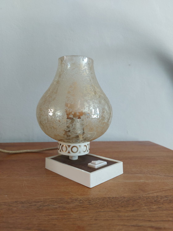 Image 1 of vintage tafellamp met een witte basis en een kap van gestructureerd, amber glas. 