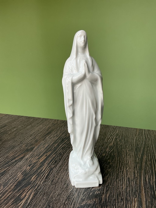 Estatua de porcelana de la Virgen María bajo una cúpula de cristal.