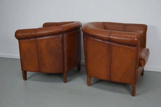 Image 1 of Dit paar cognackleurige leren clubfauteuils komt uit Nederland. Ze zijn bekleed met cognackleurig leer en zijn voorzien van meta
