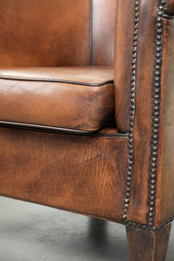 Image 1 of Schapenleren clubfauteuil met een mooie patina en een verfijnde afwerking met zwarte biezen