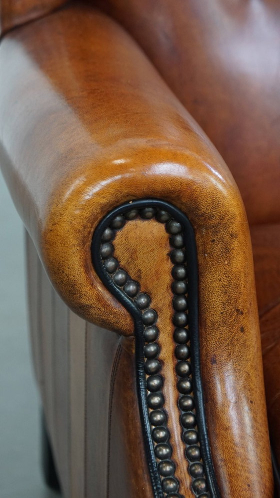 Image 1 of Comfortabele schapenleren oorfauteuil met een prachtige warme kleurstelling en een afwerking met stiksels en zwarte biezen