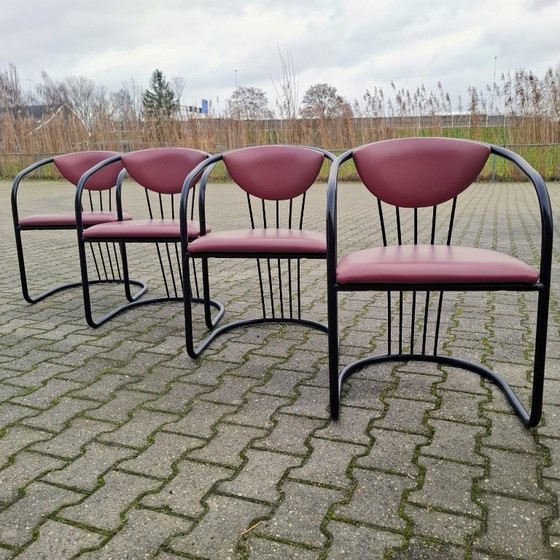 Image 1 of This is a set of four vintage 'Memphis' style chairs with a black metal frame and burgundy upholstery.