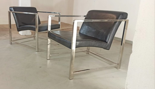 Set van 2 zwarte leren fauteuils met chromen accenten.