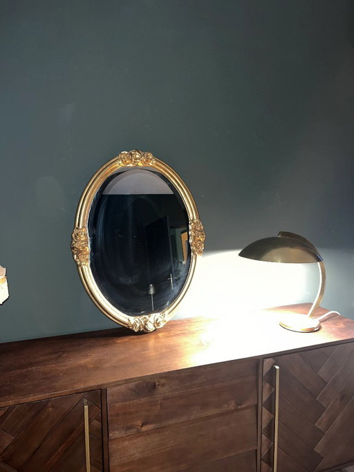 Oval Art Nouveau / Art Déco mirror with facet cut. Original vintage with golden frame and rose decoration.