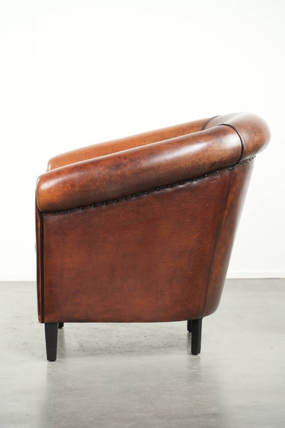 Image 1 of Mooie en karaktervolle schapenleren clubfauteuil met mooie diepe warme kleuren, zwarte biezen en een comfortabele zit