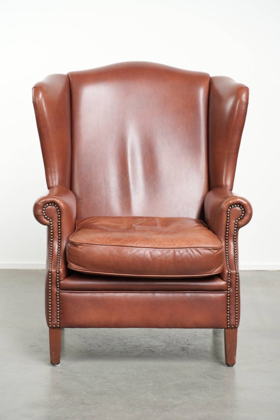 Image 1 of Comoda poltrona a orecchioni in pelle bovina color cognac in stile inglese.