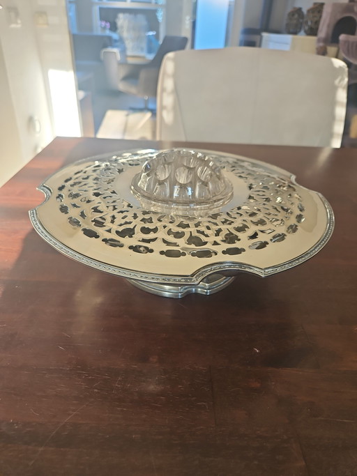 Bol de metal plateado con tapa perforada y soporte para flores.