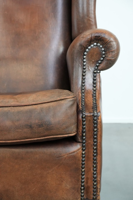 Image 1 of Caratteristica poltrona vintage di grandi dimensioni con ali laterali, realizzata in pelle di pecora.