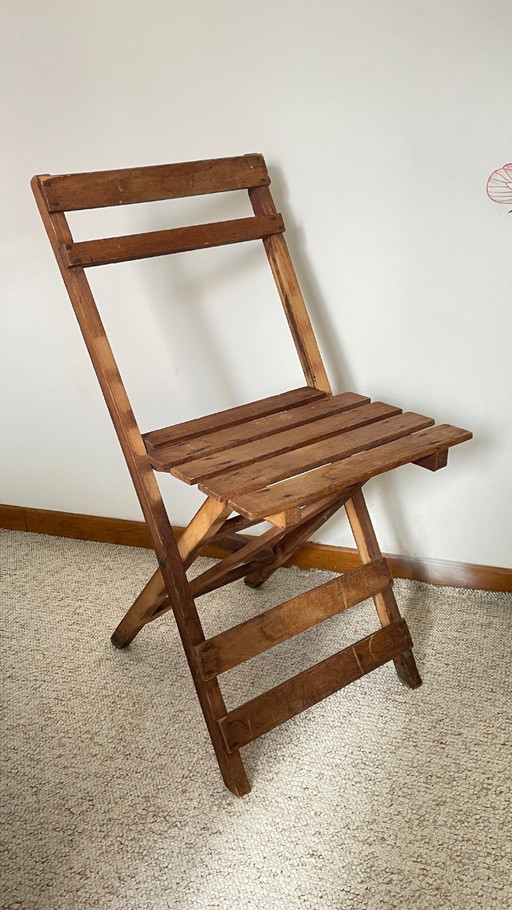 Antieke opklapbare houten stoel, een praktische en geometrische zitplaats. We zijn helemaal gecharmeerd van deze antieke stoel.
