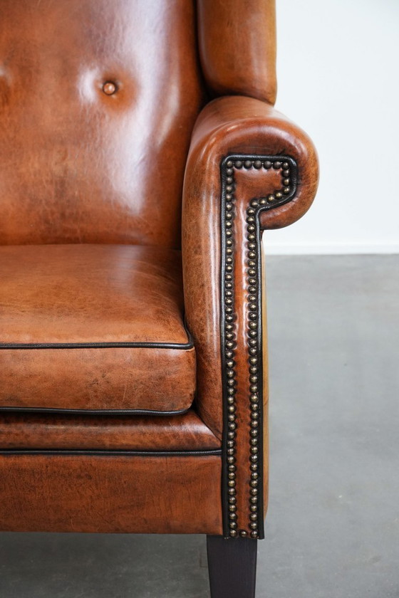 Image 1 of Grote schapenleren oorfauteuil met zwarte biezen en siernagels