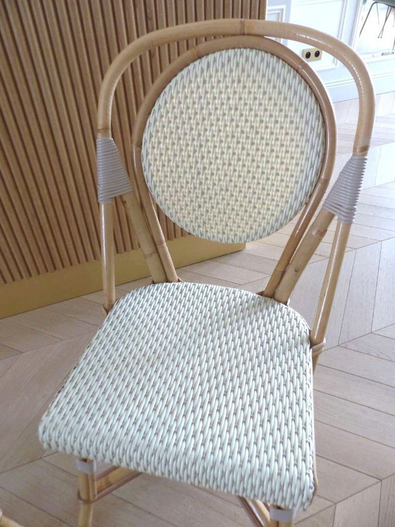 Image 1 of Een paar Parijse bistrostolen van Maison Louis Drucker in licht Manila-rotan.
