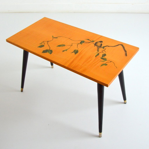 Pretty coffee table from the 50s/60s.  Decorated with a bird on a branch.  Black brass-finish tapered legs.  L 80/ W 40/ H 51