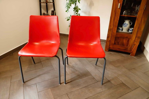 Paar rote Kunststoffstühle mit Metallgestell