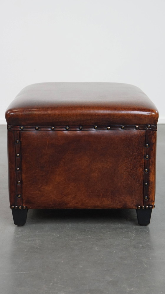 Image 1 of Cognac-kleurige schapenleren hocker met siernagels