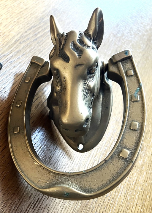 Aldaba de puerta con forma de cabeza de caballo sobre una herradura