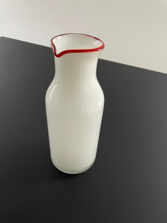Image 1 of Caraffa dal design scandinavo in vetro bianco con bordo rosso.