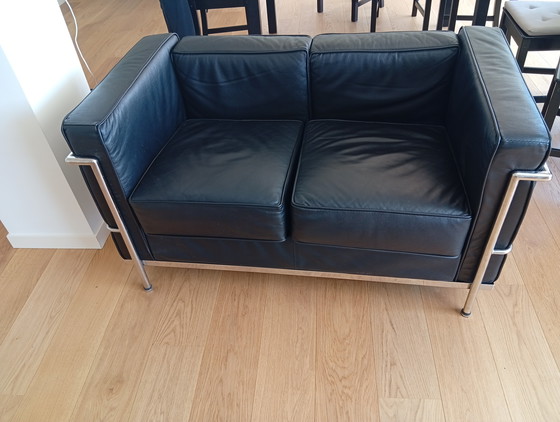 Image 1 of Een set van twee zwarte leren fauteuils en een bank.